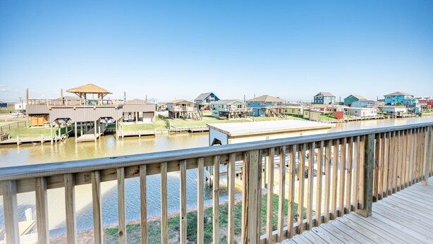 Une propriété située au bord de l’eau, dotée d’une terrasse en bois, de plusieurs bâtiments et offrant une vue sur un ciel dégagé.