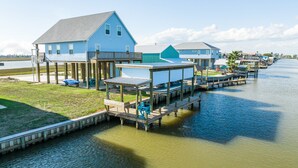 Une propriété située au bord de l’eau, avec plusieurs bateaux amarrés, une pelouse et une maison dotée d’un balcon.