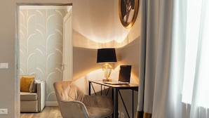 A modern living room with a sofa, a chair, a desk with a laptop, a lamp, and a wall-mounted air conditioner. - San Pier Maggiore Abbess's Suite (Firenze)
