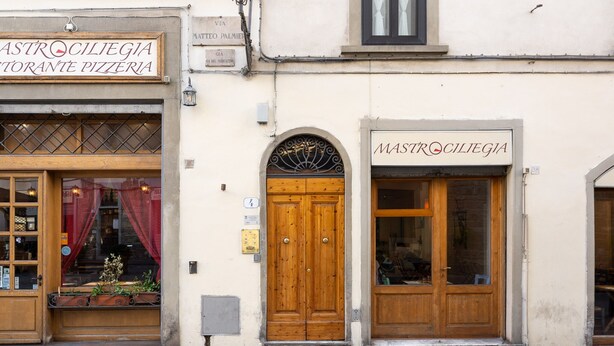 A building with two storefronts, each with a wooden door and a sign above. - San Pier Maggiore Abbess's Suite (Firenze)