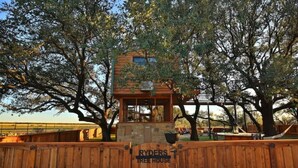 Ein Baumhaus mit Holzfassade und einem Schild, auf dem 'RYDERS TREE HOUSE' steht.