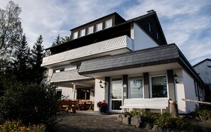 A modern two-story house with a balcony, large windows, and a stone pathway leading to the entrance. - Bauernhofpension Hof Dödesberg (Bad Berleburg)