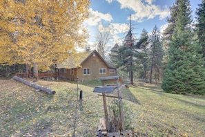 Situated in a forested area, this cabin features a traditional design with a gabled roof and chimney.