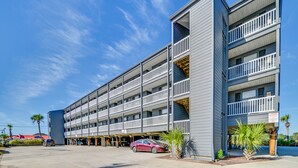 A multi-story parking garage with a modern design, featuring a series of balconies and a covered entrance area. - Murrells Inlet Condo w/ Balcony & Pool: Near Pier! (Murrells Inlet)