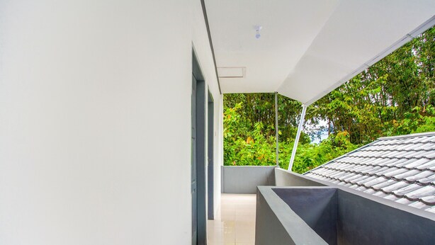 Un edificio moderno con un lungo e stretto corridoio che conduce a un balcone con tetto in tegole.