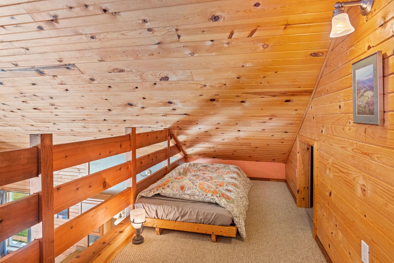 Une chambre à coucher dans un chalet en bois, avec un lit simple, une table de chevet, une lampe et un tableau encadré au mur.
