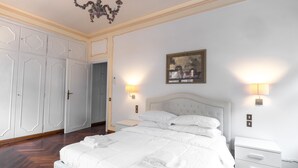 Une chambre à coucher avec un grand lit, un lustre, un tableau au mur et une armoire.