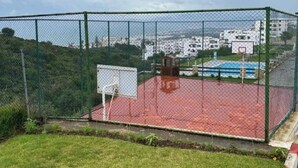 Ein Basketballplatz im Freien mit einem Zaun aus Maschendraht, einem Korb und einer roten Spielfläche.