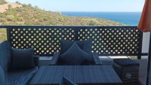Ein Balkon mit Korbmöbeln und Blick auf das Meer.