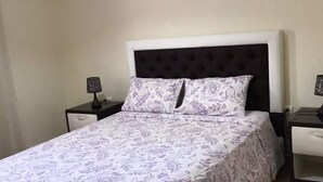 Ein Schlafzimmer mit einem Bett, zwei Nachttischen und einem Kopfteil.