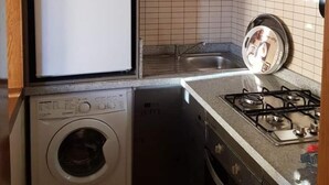 Eine kompakte Küche mit Kühlschrank, Waschmaschine und Herd.