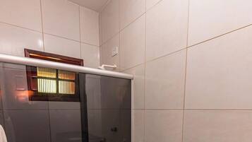 A modern bathroom with a glass-enclosed shower, a white toilet, and a black marble sink.
