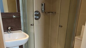 Une salle de bain avec une douche à parois de verre, un lavabo blanc et des toilettes.