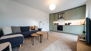 A modern living room with a sofa, two round tables, and a herringbone-patterned floor.