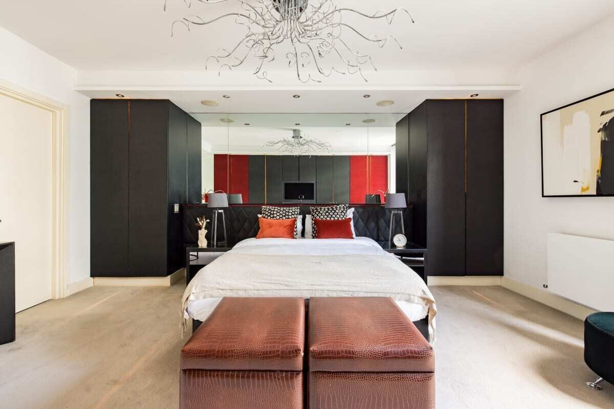 A modern bedroom with a large bed, a chandelier, and a TV.