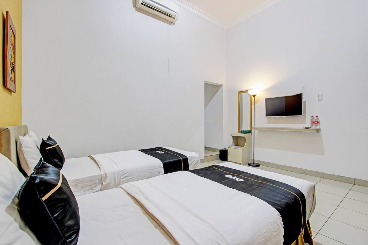 A hotel room with two beds, a TV, and a mirror.