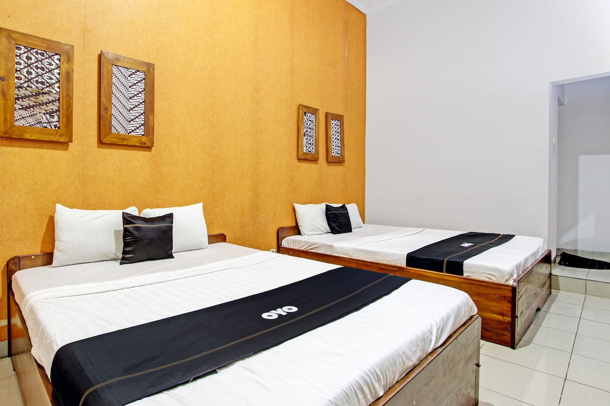 A hotel room with two beds, wooden headboards, and patterned wall decorations.