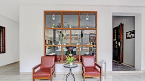 A room with two red leather chairs, a small round table, and a large window with multiple panes and hanging lanterns. - Super OYO Capital O 93240 Candra Dewi Hotel (Yogyakarta)