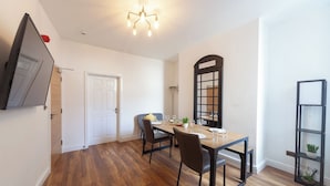 A dining area with a wooden table, chairs, and a chandelier. - Beautiful 7 bedroom Victorian home in Lancashire (Morecambe)
