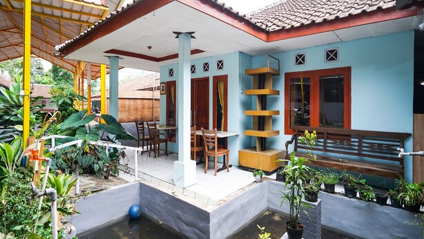 Ein Haus mit überdachter Terrasse, kleinem Pool und verschiedenen Kübelpflanzen.