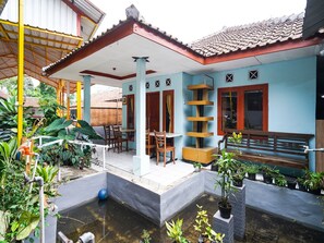 Una casa con porche cubierto, piscina pequeña y plantas en macetas.