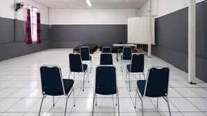 Ein Konferenzraum mit weißen Fliesen, blauen Stühlen, einem weißen Tisch und einer Projektionsleinwand.