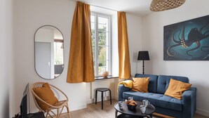 Ein modernes Wohnzimmer mit einer Couch, einem Sessel, einem Couchtisch und einem Fernseher.