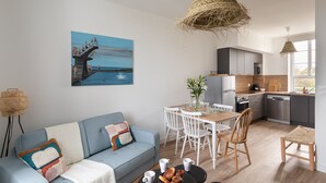 Ein modernes Wohnzimmer mit Sofa, Esstisch und Küchenbereich.