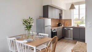 Eine moderne Küche mit grauen Schränken, einem Holzespeisetisch, weißen Stühlen und einer Blumenvase.