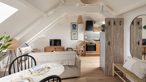 A cozy loft-style room with a dining area, kitchenette, and a large mirror. - Force 9 - Proche plage de Rochebonne (Saint-Malo)