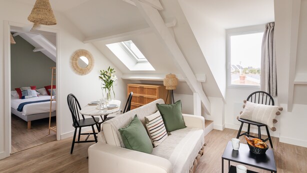 A cozy loft-style room with a sofa, dining table, and a view of the city through a skylight. - Force 9 - Proche plage de Rochebonne (Saint-Malo)