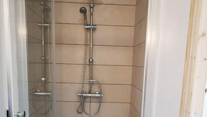 Box de chuveiro com paredes de vidro, chuveiro manual e chuveiro fixo na parede.
