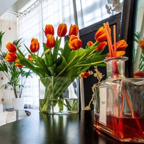 Ein Tisch mit einer Vase voller orangefarbener Tulpen und einer Karaffe mit roter Flüssigkeit und Zimtstangen.