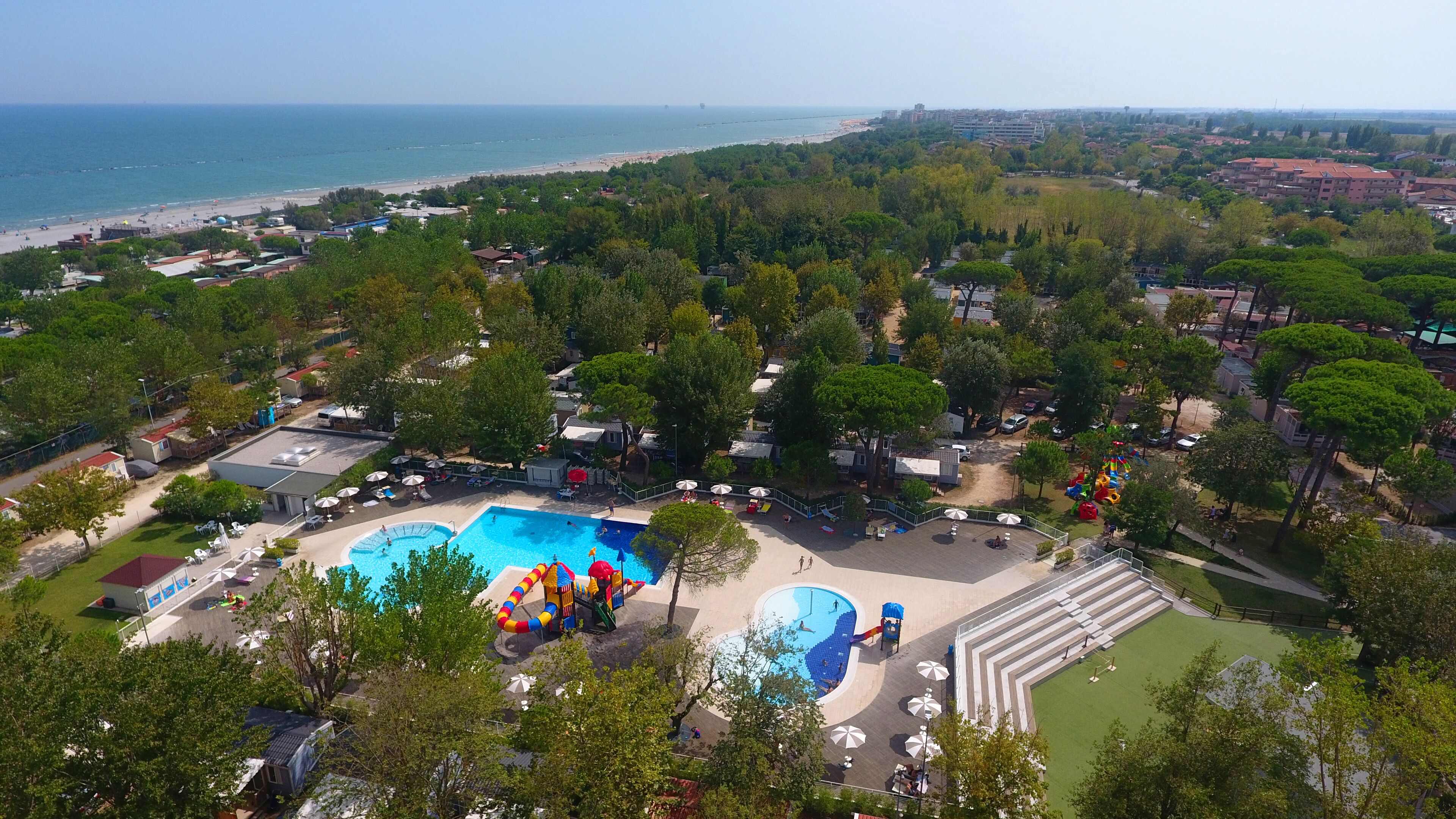 Ett flygbildsbild av ett semesterområde med en swimmingpool, vattenrutschkanor och en strand.