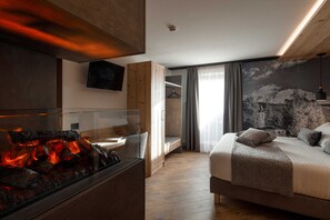 Une chambre d’hôtel moderne équipée d’un lit, d’une cheminée, d’une télévision et ornée d’une fresque murale.
