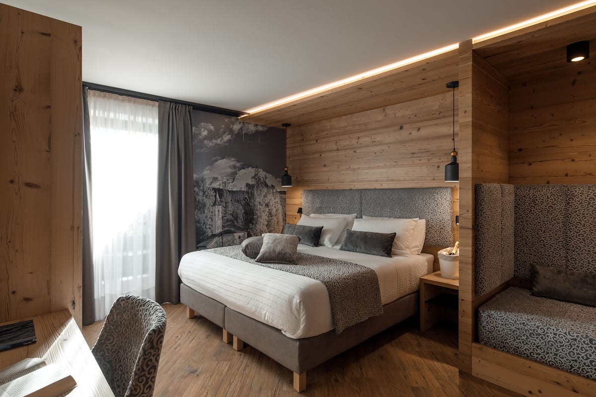 Un dormitorio moderno con una cama grande, un área de descanso y un mural en la pared.