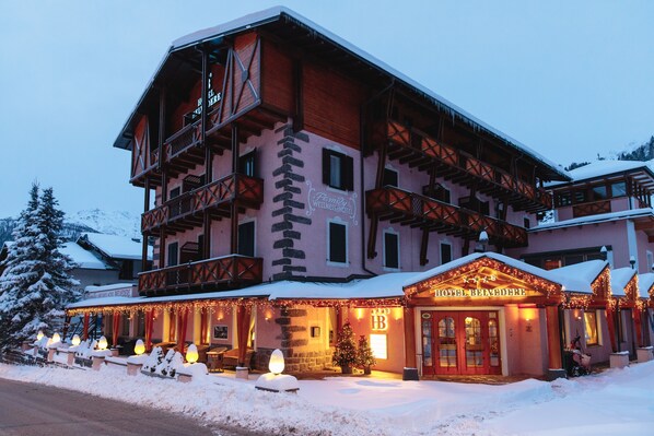 Un hôtel à plusieurs étages, de style architectural alpin traditionnel, doté de balcons et d’une entrée imposante avec une enseigne.