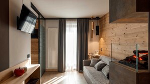 A modern living room with a sofa, a fireplace, a TV mounted on the wall, and a wooden floor.