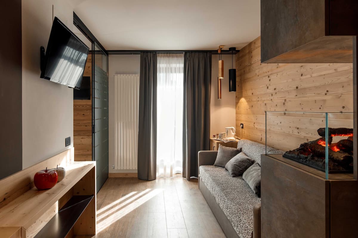 Una sala de estar moderna con un sofá, una chimenea, un televisor montado en la pared y piso de madera.