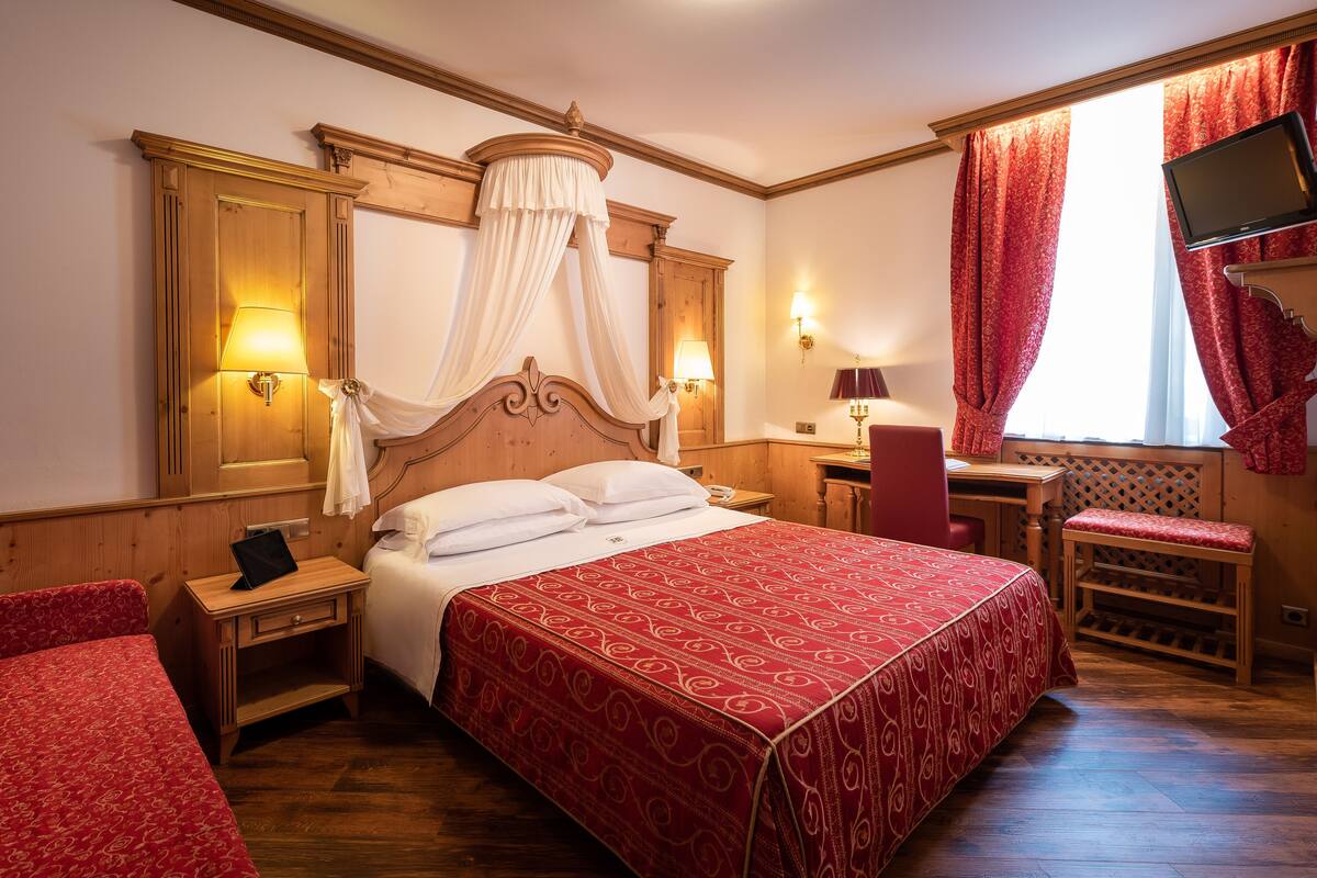 Una habitación de hotel con una cama grande, un escritorio, una silla y un televisor.
