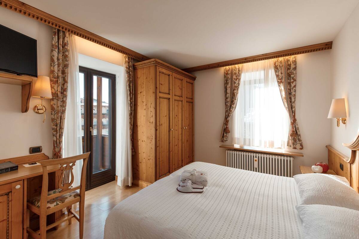 Una habitación de hotel con una cama, un escritorio, una silla, un televisor y un armario.