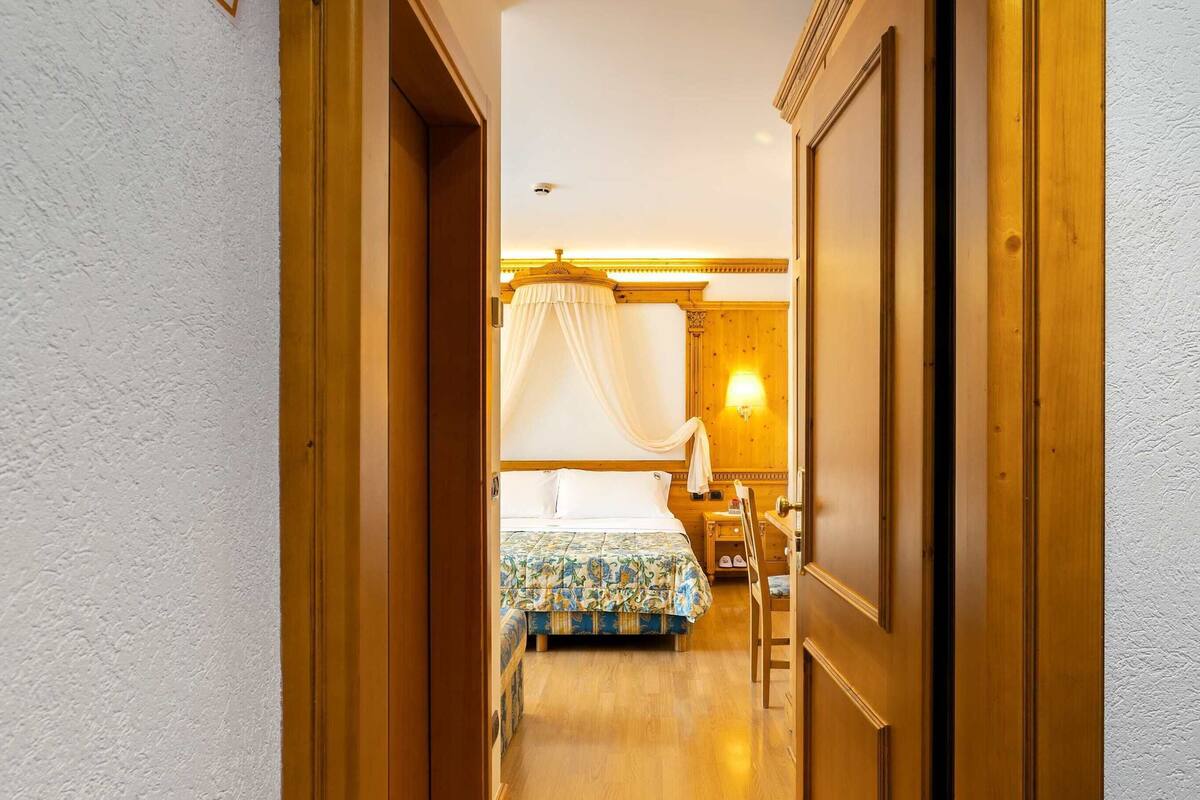 Una habitación de hotel con una cama, una mesita de noche, una lámpara y suelo de madera.