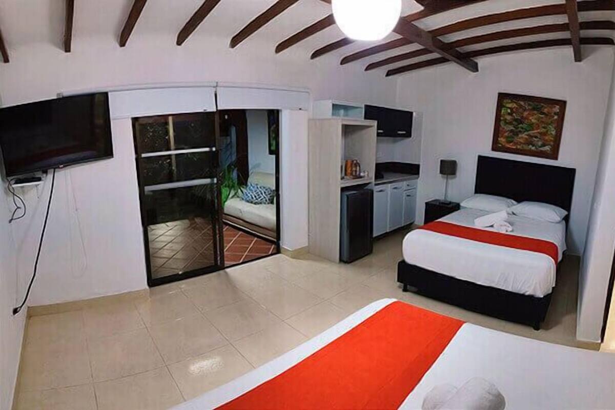 Una habitación de hotel con una cama, un escritorio, un televisor y un cuadro en la pared.