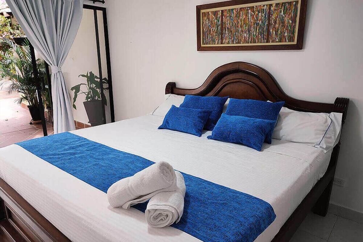 Una cama bien hecha con ropa de cama azul y blanca, un cabecero de madera y un plaid azul.