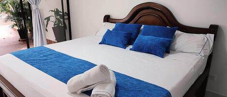 A neatly made bed with blue and white bedding, a wooden headboard, and a blue throw blanket.