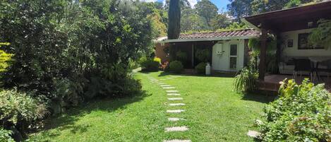 A well-maintained garden with a clear path leading to a house with a tiled roof and a porch.