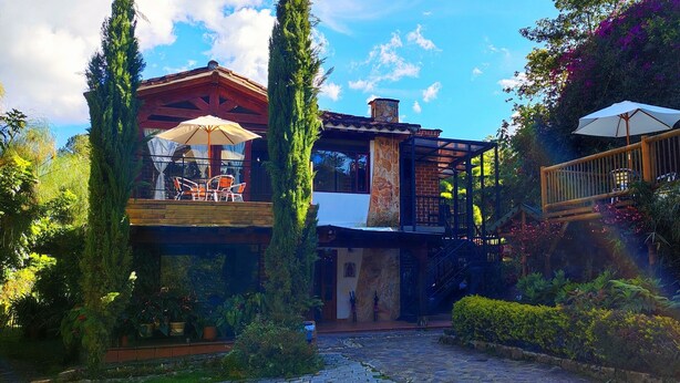 A rustic building with a stone facade, a wooden deck, and a staircase leading to a balcony.