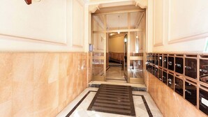Ein Hallenkorridor mit Marmorboden, einer Glaselevator und einer Reihe von Glasvitrinen auf der rechten Seite.
