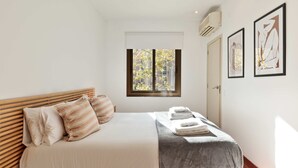 Ein Hotelzimmer mit einem Bett, einem Fenster und zwei gerahmten Kunstwerken an der Wand.