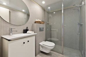 A modern bathroom with a glass-enclosed shower, a white sink with a mirror, and a toilet. - VALENCIA 2 (Barcelona)